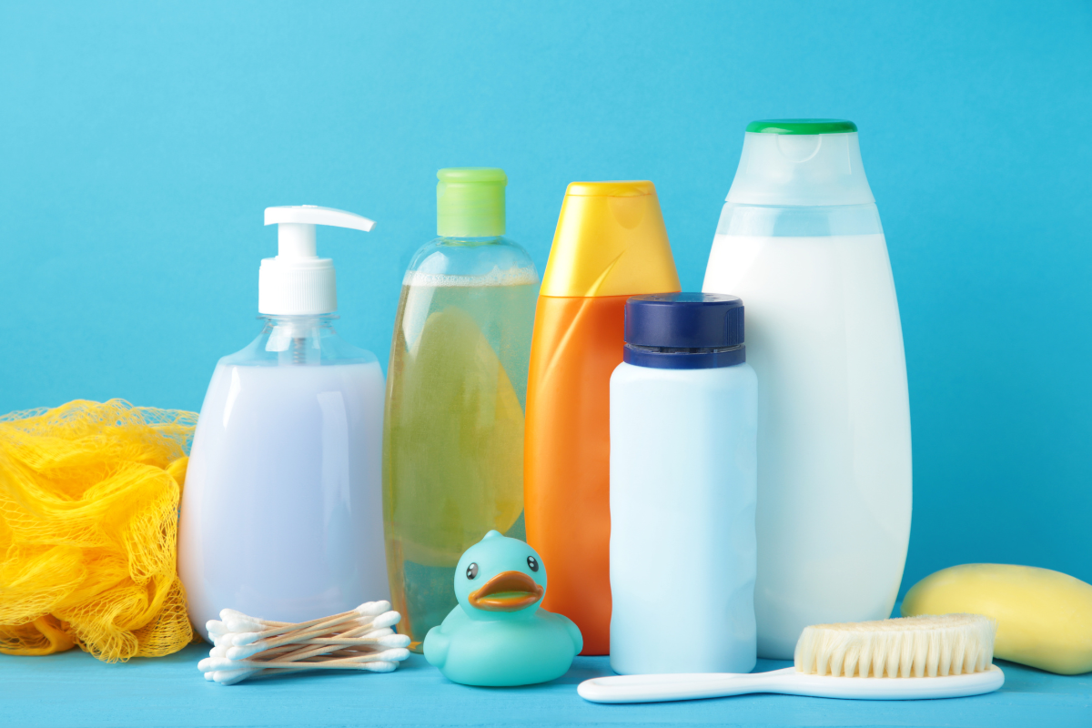 A flat lay of common household items like petroleum jelly, white toothpaste, baking soda, and dish soap on a clean towel with a comb and gloves