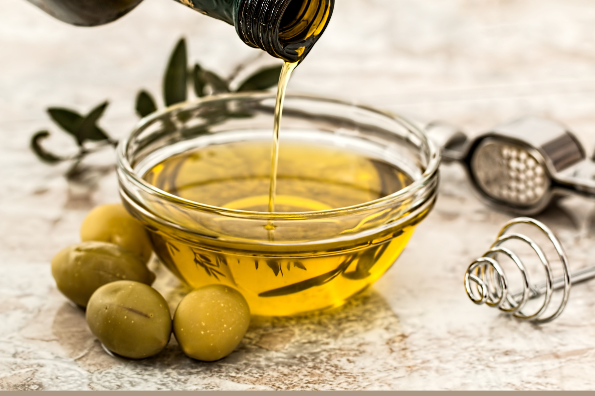 A flat lay of home remedies for removing dye_ olive oil, baking soda, petroleum jelly, makeup remover, cotton balls — nicely arranged