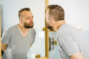 man with beard looking in mirror winter