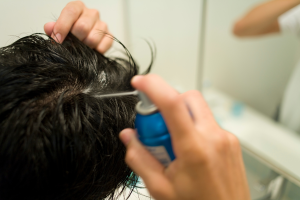 Man applying coconut oil to hair in a bathroom mirror